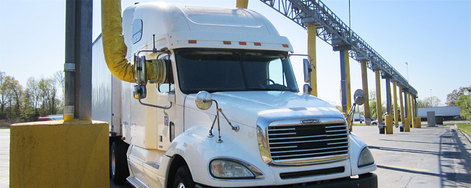 Photo of a set of truck stop electrification hookups. One of the spaces is occupied by a tractor trailer.
