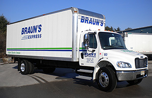 A photo of a white semi-truck with the side of the truck labeled