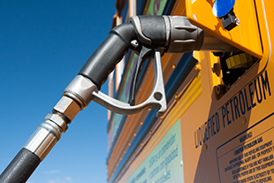 A close-up photo of a yellow school bus being re-fueled with propane.