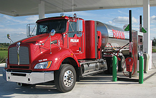 A photo of a red Class 8 truck filling up at a compressed natural gas station.