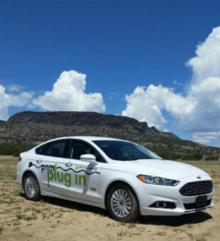 A photo of a PNM plug in electric vehicle in front of a mesa.