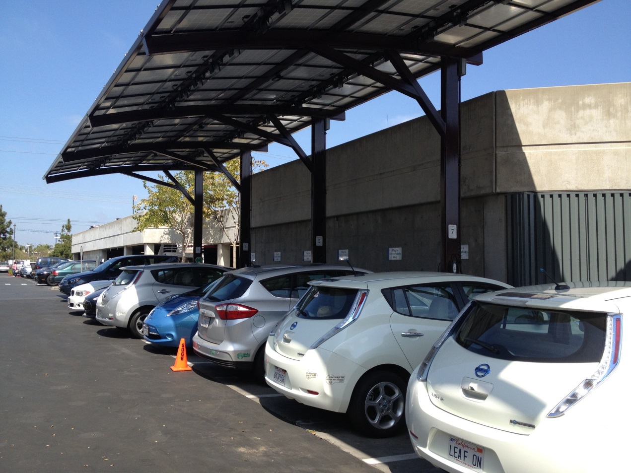 Plug-in electric vehicles (PEVs) parked under a solar canopy with access to electric vehicle supply equipment.